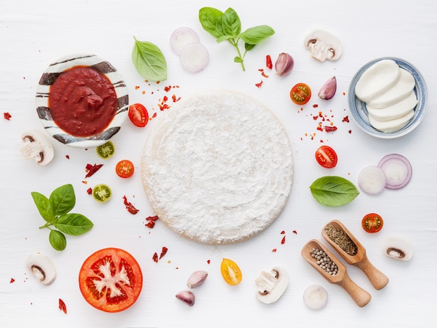 The ingredients for homemade pizza on white wooden background.