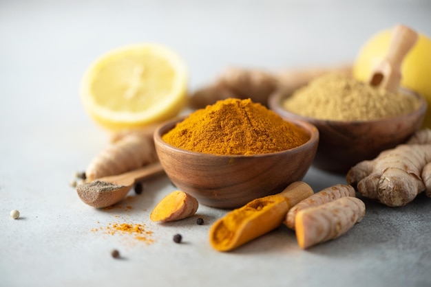 Ingredients for hot ayurvedic drink Turmeric powder curcuma root cinnamon ginger lemon over grey background Copy space square crop Spices for alternative medicine