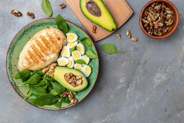 Ingredients for a ketogenic diet avocado grilled chicken fillet quail egg spinach walnut Healthy fats clean eating for weight loss Food recipe background Close up top view