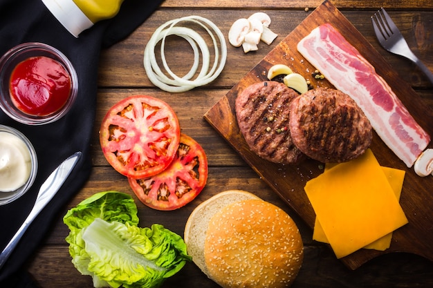 Ingredients to make hamburger at home, bread, meat, tomato, lettuce bacon and cheese.