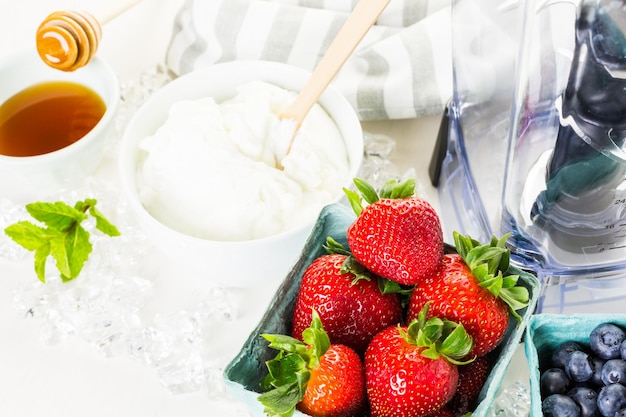 Ingredients to make smoothie with plain yogurt and fresh berries on the table.