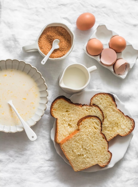 Ingredients for making baked French brioche toasts eggs milk cane sugar pieces of fresh homemade brioche on a light background top view