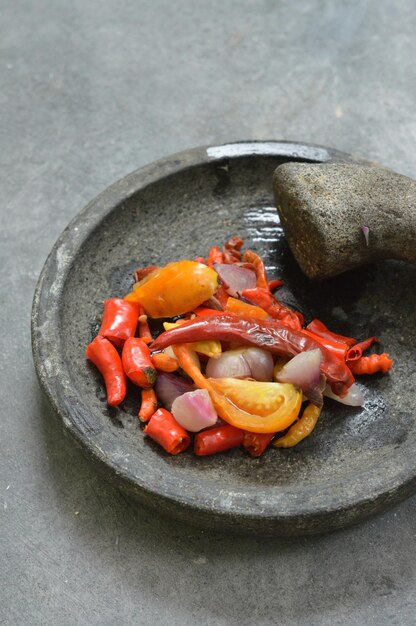 Photo ingredients for making chili sambal on the stone grinder