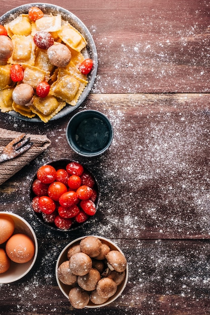 Ingredienti per la preparazione di ravioli fatti in casa con salsa di funghi su un vecchio tavolo di legno. cibo vegano italiano. copyspace