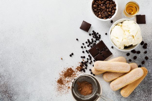 Ingredients for making Italian dessert tiramisu, savoiardi, mascarpone, cocoa powder and chocolate on a light concrete