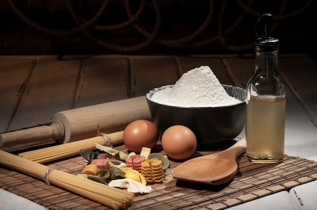 Ingredients for making pasta on a wooden table. Copy space. Uncooked pasta with flour on the table.