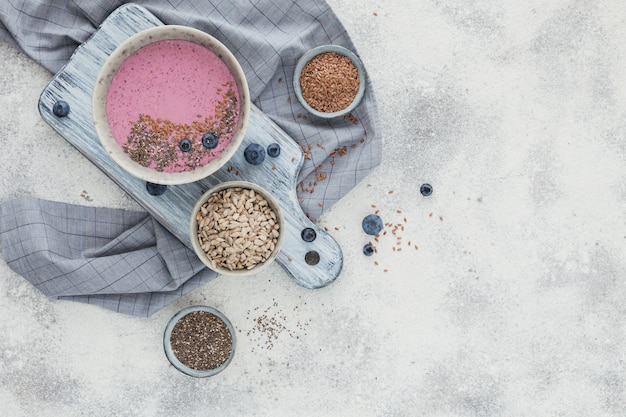 Ingredients for making pink yogurt smoothie bowl with fresh blueberry and seeds. Top view, free space