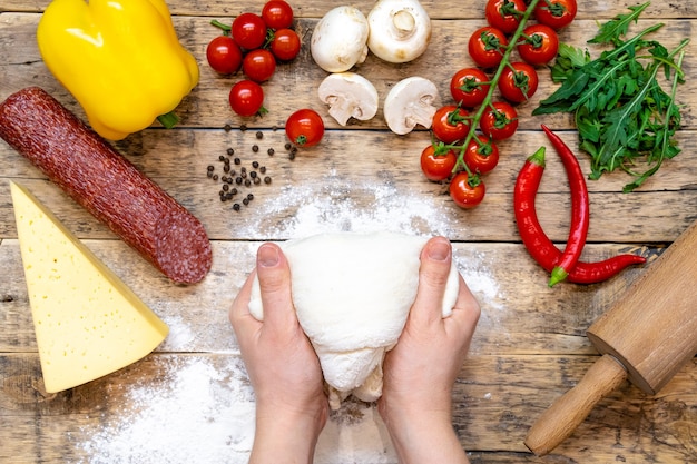 Ingredients for making pizza, before baking, on a wooden table, top view, step-by-step recipe