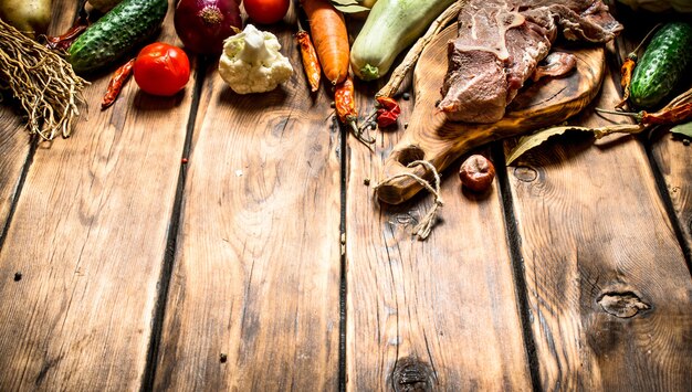 Ingredients for making soup with beef. On wooden background.