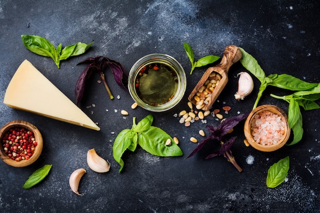 Gli ingredienti per fare il pesto italiano tradizionale salsa su vecchio fondo rustico scuro. disteso.