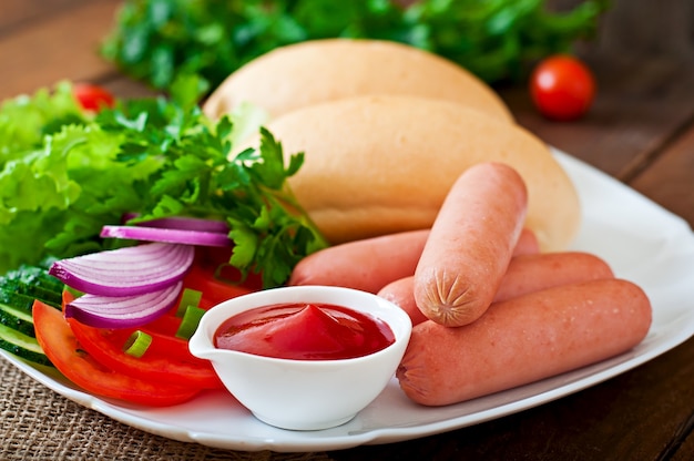 Ingredients for the preparation of hot dogs on a white plate