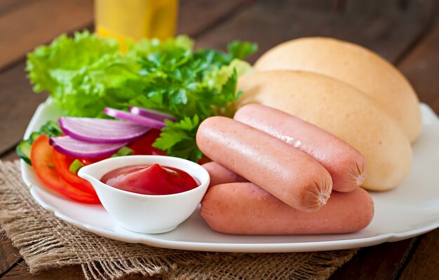 Ingredients for the preparation of hot dogs on a white plate