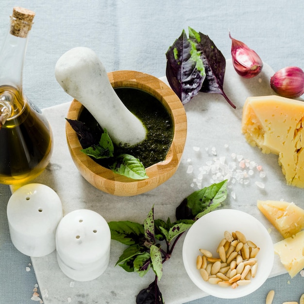 Ingredients for the preparation of Italian basil purple pesto with cheese on linen blue tablecloth