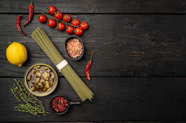 Ingredients for preparation spaghetti with calms or mussels set on black wooden table background top view flat lay with copy space for text