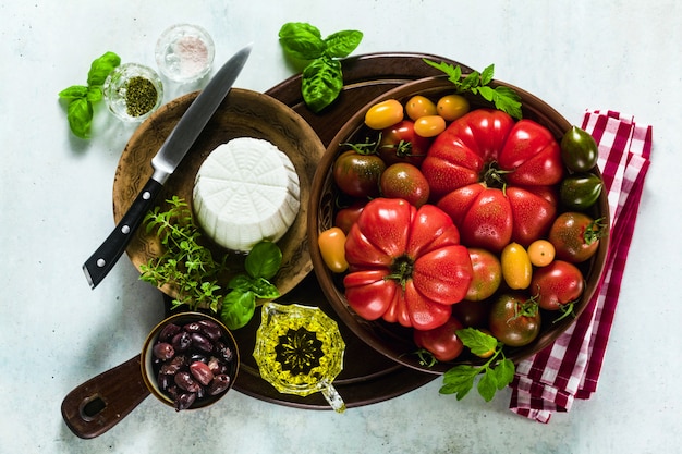 Ingredienti per la preparazione di insalata estiva di pomodori colorati, olive e ricotta. ricette mediterranee