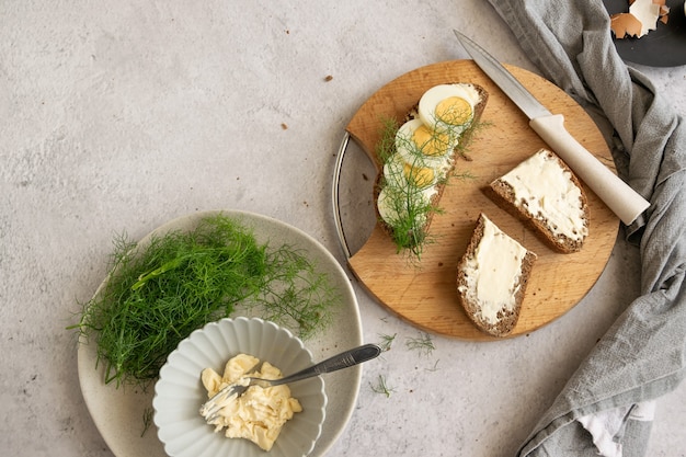 Ingredients for preparing healthy farm breakfast - eggs, whole wheat black bread, goat cream cheese and fresh raw fennel