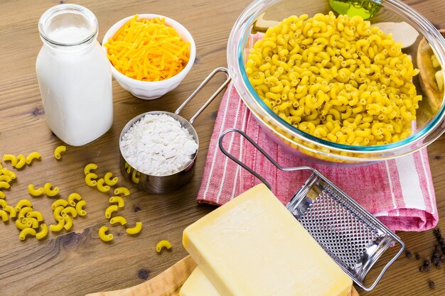 Ingredients for preparing macaroni and cheese on a wood table.