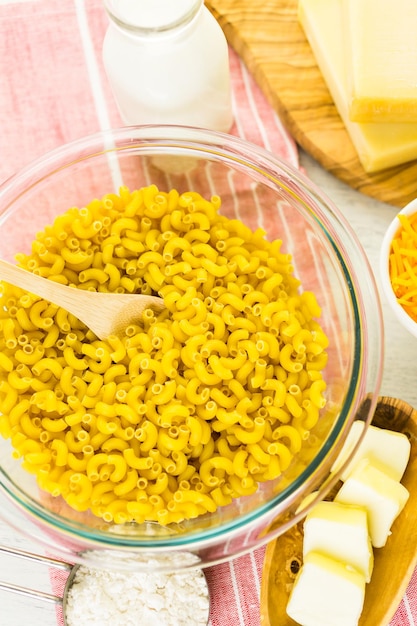 Ingredients for preparing macaroni and cheese on a wood table