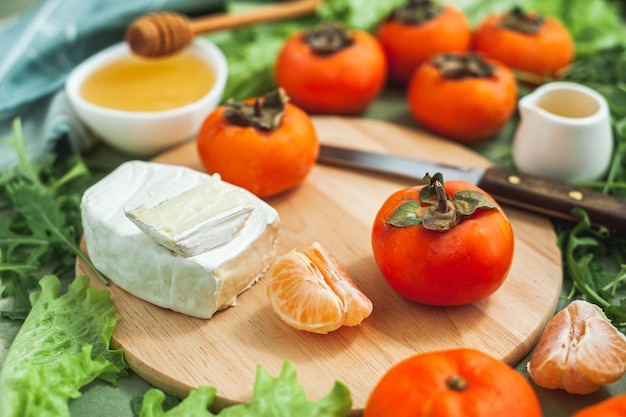 Ingredients and the process of making a vitamin winter salad with persimmons tangerines and cheese