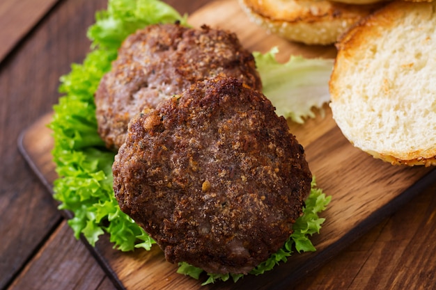 Ingredients for a sandwich - hamburger burger with beef, pickles, tomato and red onion on wooden background.