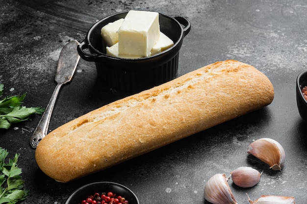 Ingredients for sandwich with butter, herbs and baguette set, on black dark stone table background