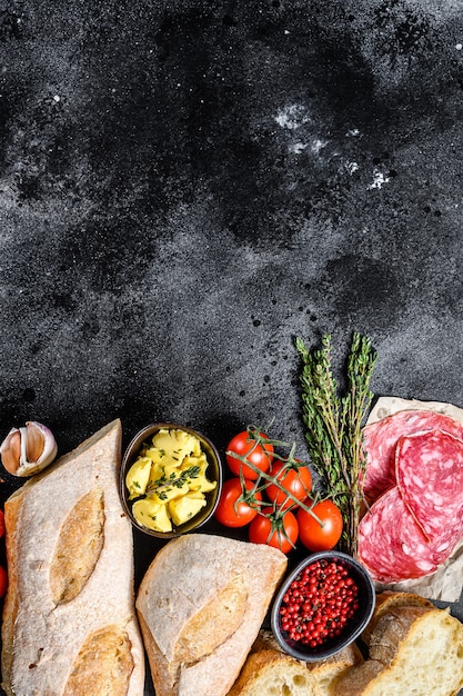 Ingredients for sandwich with butter, smoked meat, baguette, cherry tomatoes, parmesan cheese, garlic and spices. top view. Copy space