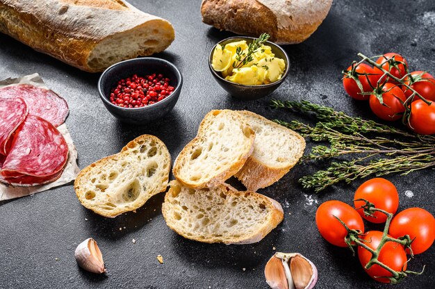 Ingredients for sandwich with butter, smoked meat, baguette, cherry tomatoes, parmesan cheese, garlic and spices