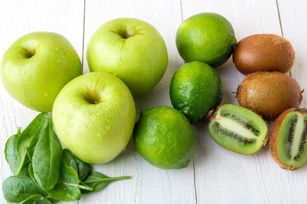 Ingredients for smoothie. Green fruits on white wooden . Apple, lime, spinach, kiwi. Detox. Healthy food.