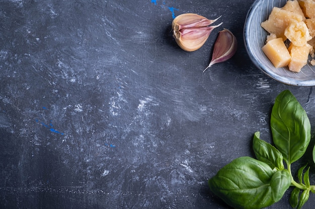 Ingredients and spice for cooking. Basil, garlic and cheese on a dark table. Copy space.