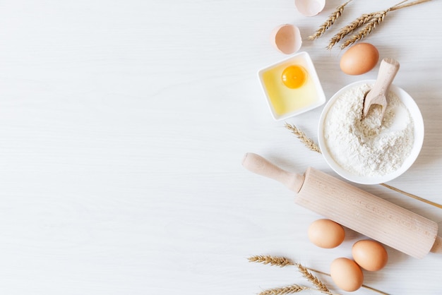 Ingredients and tools for dough preparation on white wooden background top view