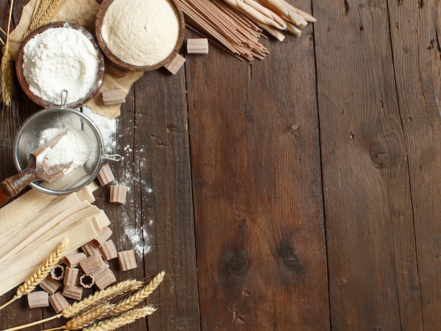 Ingredients and utensils for pasta making on a wooden background