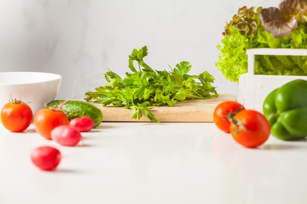 Ingredients for vegetable salad on a white table, copy space. Healthy vegan lifestyle concept.