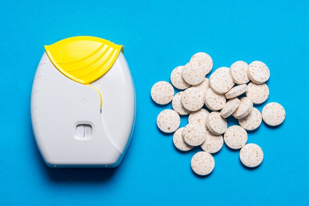 Inhaler and tablets on blue background