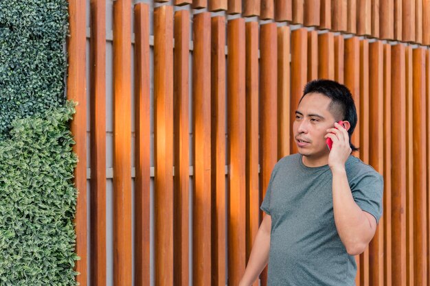 Inheemse man die over straat loopt terwijl hij op mobiele telefoon praat