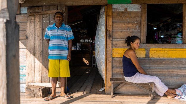 Inheemse man en vrouw buiten hun houten huis