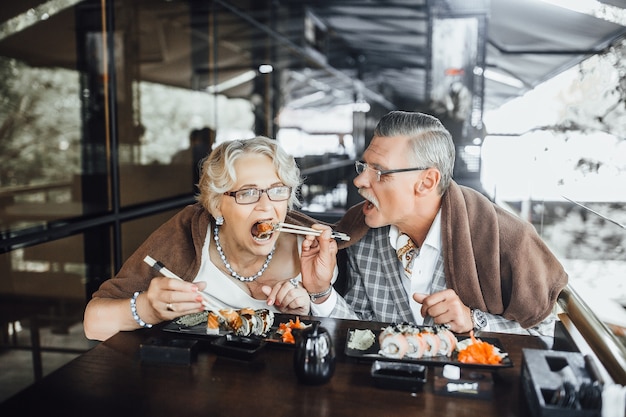 Foto inhoud man en vrouw zitten op zomerterras sushi eten en samen tijd doorbrengen