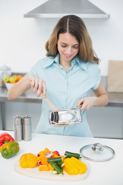 Inhoudsvrouw die terwijl status in keuken koken