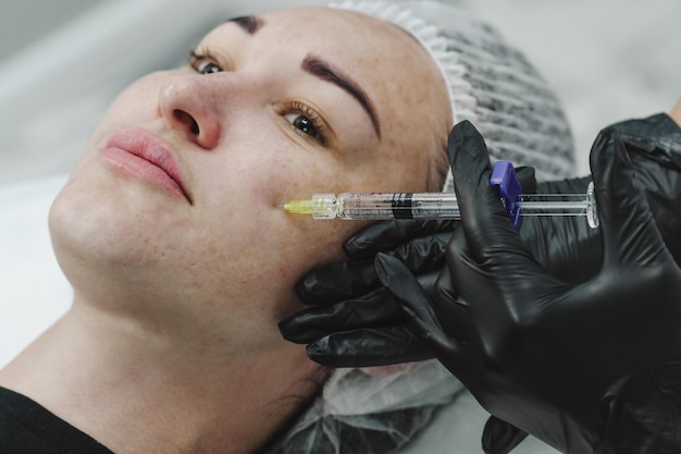 Foto injectie cosmetologie cosmetoloog geeft een injectie op het gezicht schoonheid injecties