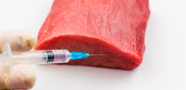 Инъекция в сырое мясо на белом фоне Концептуальная иллюстрация гормонов и антибиотиков в производстве продуктов питания