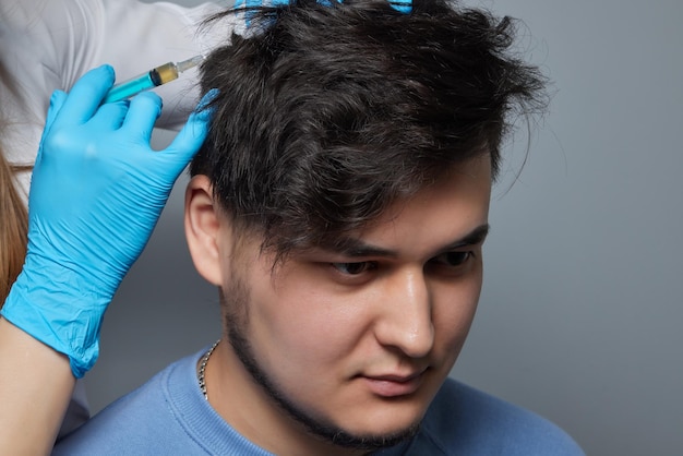 Foto iniezione di plasma nel medico cosmetologo uomo capelli testa