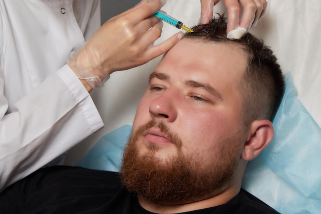 Foto iniezione di plasma nel medico cosmetologo uomo capelli testa