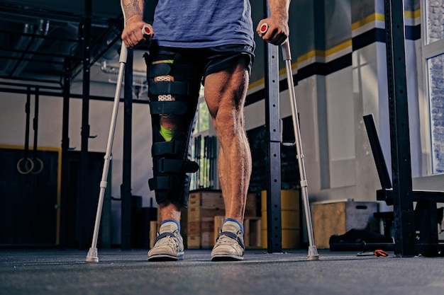 Injured bodybuilder's leg in bandage with crutches.