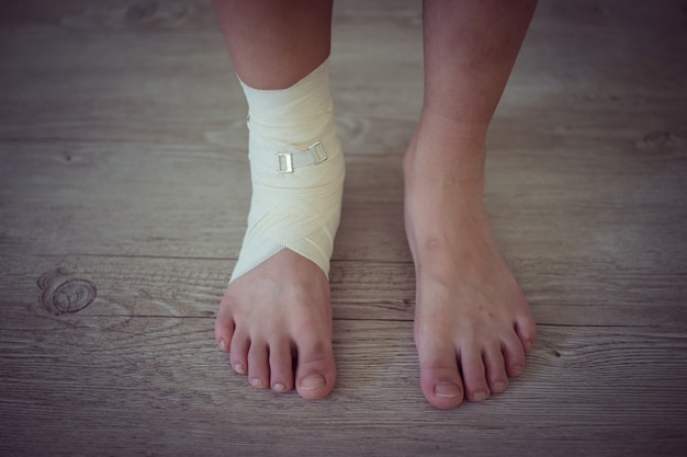 Photo injured foot on a wooden floor background