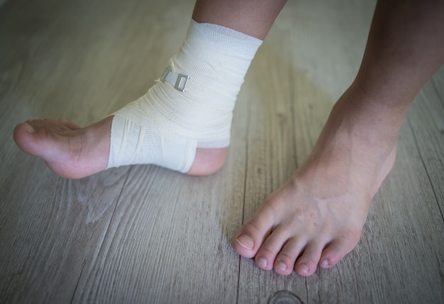 Photo injured foot on a wooden floor background