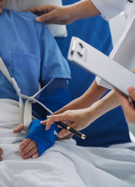 Foto paziente ferito che mostra al medico il polso e il braccio rotti con bendaggio nell'ufficio dell'ospedale o al pronto soccorso