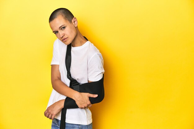 Photo injured young woman with arm brace yellow studio background