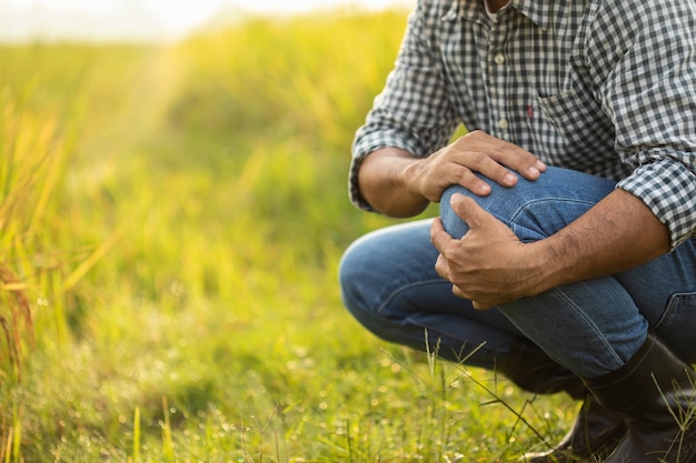 Injuries or Illnesses that can happen to farmers while working Man is using his hand to cover over knee because of hurt pain or feeling ill