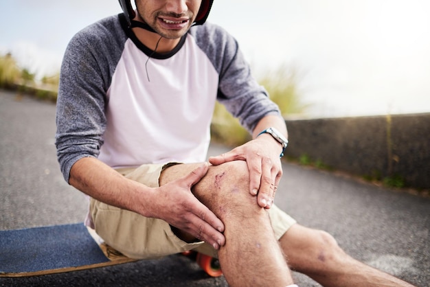 Foto ferito uomo e dolore al ginocchio dopo la pratica dell'incidente con lo skateboard e imparando a pattinare attivo cattivo e skateboarder con un livido osso rotto o tenendo una gamba dolorante per strada mentre pattina