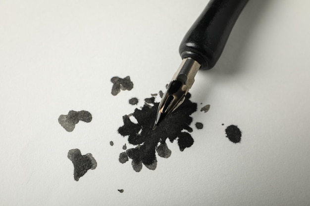 Фото Чернильное пятно и ручка на белом фоне крупным планом