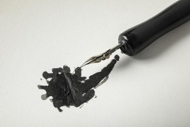 Photo ink blot and pen on white background close up